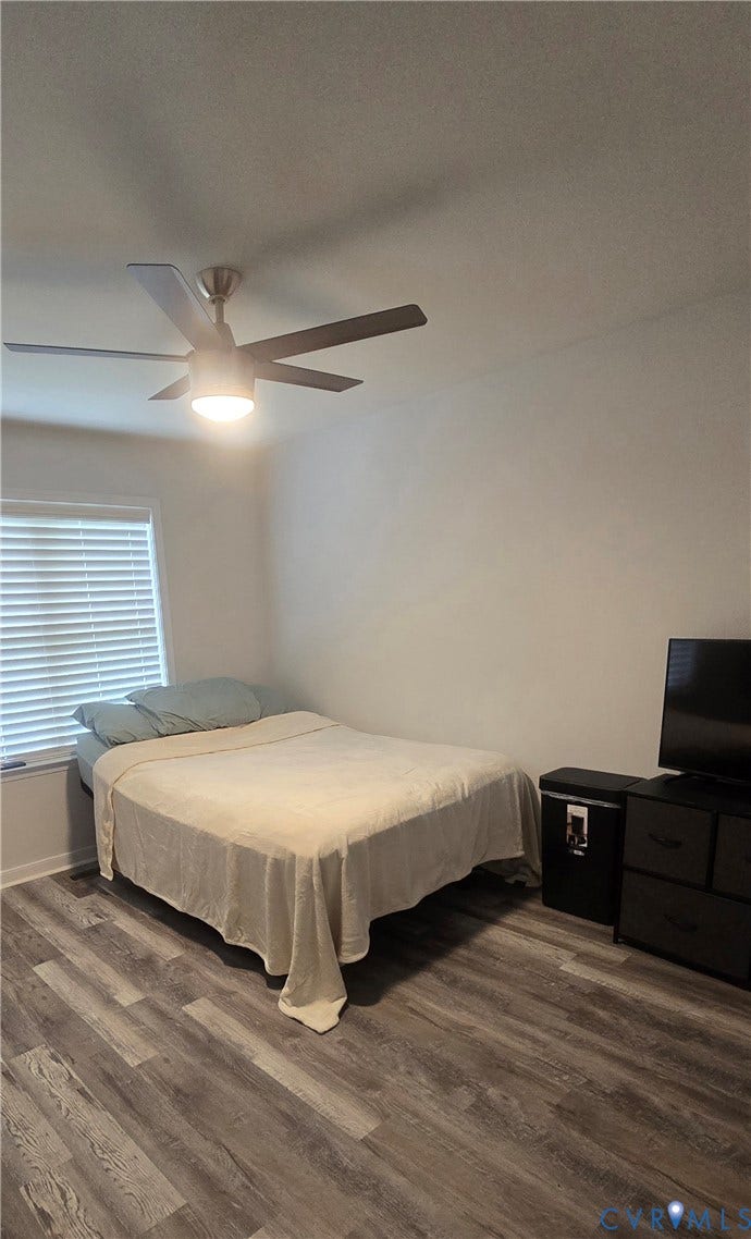 12812 Winfree Street, Chester, VA 23831 Spacious room featuring wood-finish flooring, a window with horizontal blinds, and a ceiling fan with integrated lighting