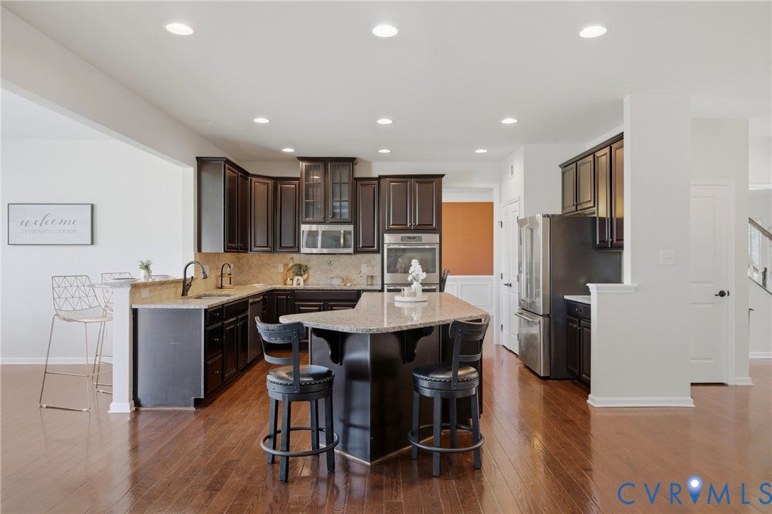 1819 White Mountain Drive, Mount Blanco On The James, Chester, VA 23836 Spacious kitchen featuring dark wood cabinetry, granite countertops, stainless steel appliances, and a central island with seating