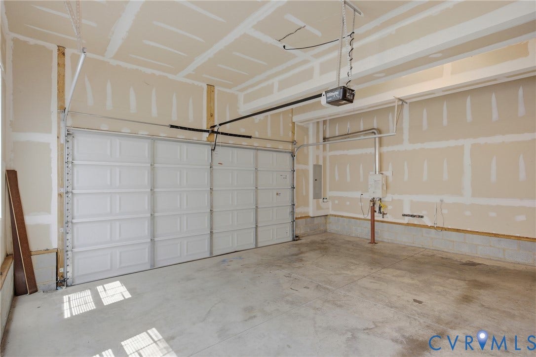 1819 White Mountain Drive, Mount Blanco On The James, Chester, VA 23836 Garage space featuring a white sectional garage door with an automatic opener, exposed drywall, concrete flooring, and visible utility conduits