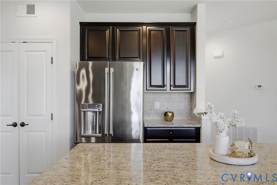 1819 White Mountain Drive, Mount Blanco On The James, Chester, VA 23836 Kitchen with a spacious stone-finish island countertop, dark wood-finish cabinetry, stainless steel refrigerator, and light tile backsplash