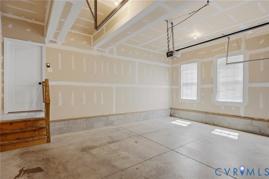 1819 White Mountain Drive, Mount Blanco On The James, Chester, VA 23836 Spacious garage featuring concrete flooring, unpainted drywall, two windows with blinds, and a garage door opener system