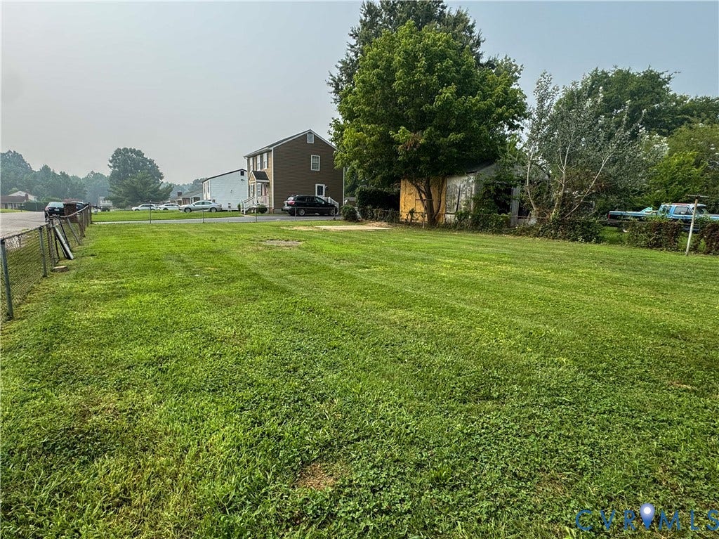 Expansive green lawn with a chain-link fence border