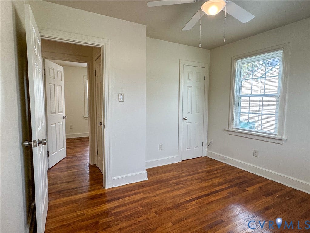 Room featuring wood-finish flooring, white walls, and a ceiling fan with integrated lighting