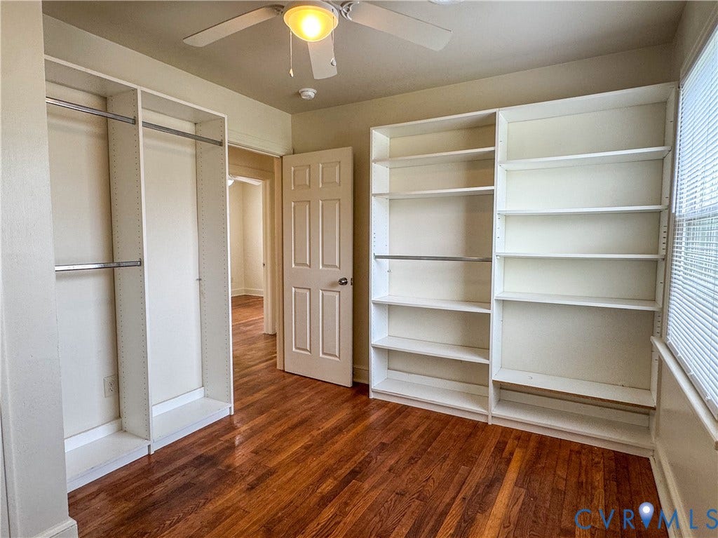 Room featuring built-in shelving, wood-finish flooring, and a ceiling fan with light fixture