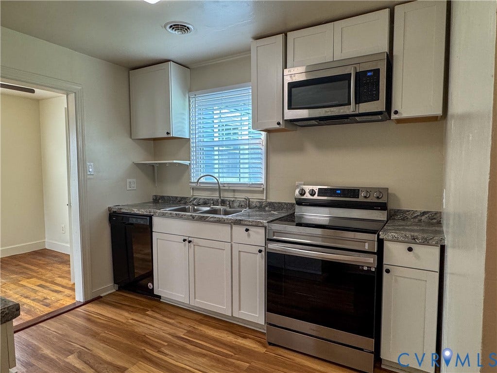 Updated kitchen featuring white shaker-style cabinetry, granite-look countertops, and wood-finish flooring
