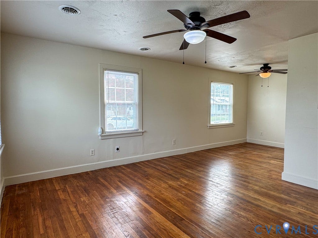 Spacious room featuring wood-finish flooring, multiple windows, two ceiling fans with integrated lighting, recessed lighting, and white baseboards