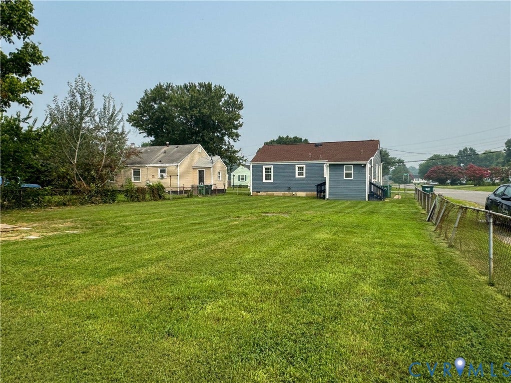 Expansive green lawn with a chain-link fence, offering a deep lot
