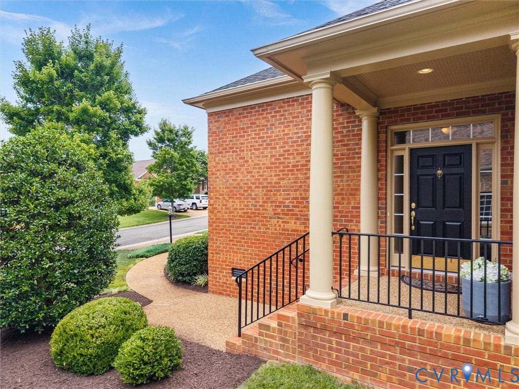 2214 Founders View Lane, Fb Golf Villas, Powhatan, VA 23113 Brick exterior featuring a covered portico with fluted columns, a black paneled entry door with transom and sidelights, black wrought iron railings, and a gravel pathway