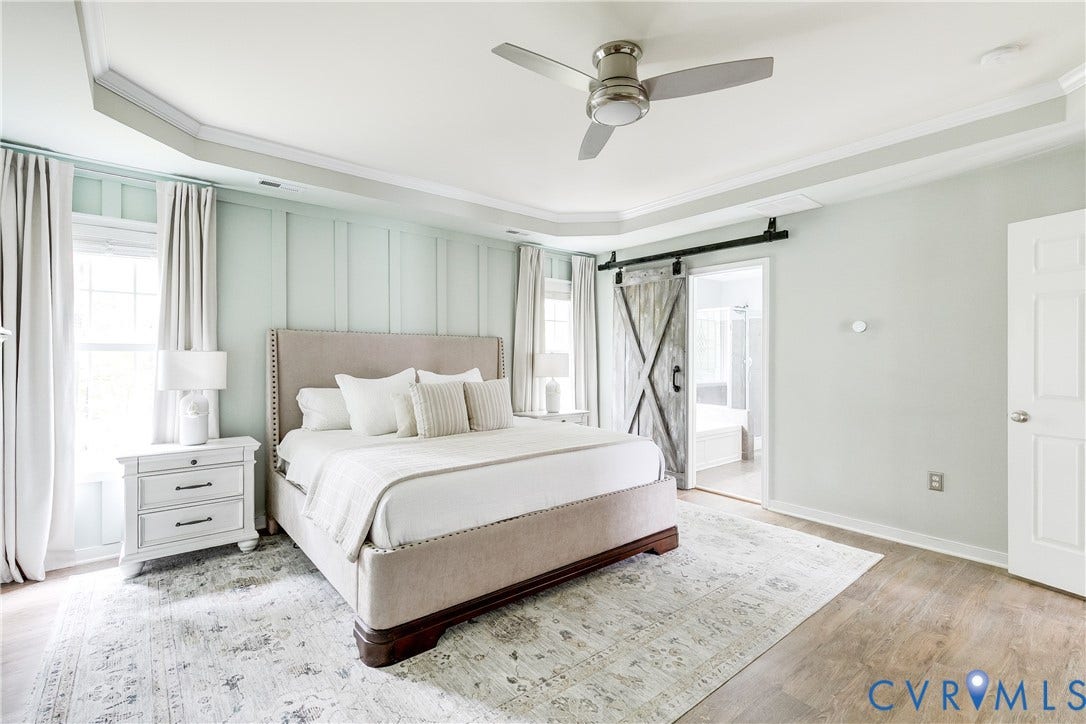 4907 Winding Branch Road, Moseley, VA 23120 Recessed tray ceiling with crown molding, plank accent wall, LVP flooring, and a sliding barn door leading to en suite