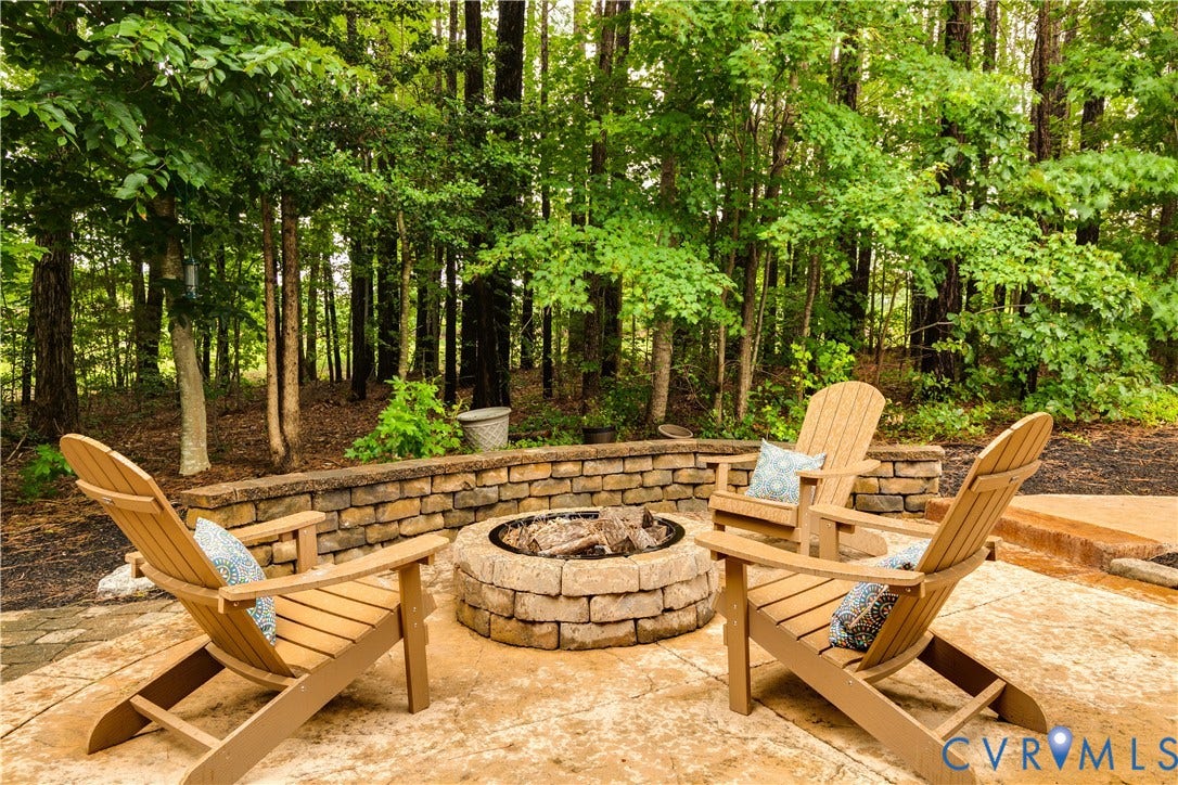 4907 Winding Branch Road, Moseley, VA 23120 Stone fire pit with a surrounding patio, featuring a stone retaining wall and mature trees