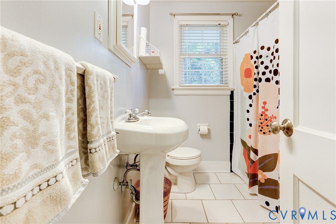 1401 Chowan Road, Henrico, VA 23229 Bathroom featuring a white pedestal sink with chrome fixtures, a window with blinds, a toilet, a shower area with a curtain rod, and white tile flooring