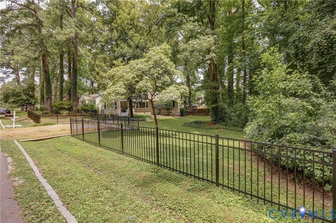 1401 Chowan Road, Henrico, VA 23229 Expansive front yard featuring a black metal fence, mature trees, and a manicured lawn