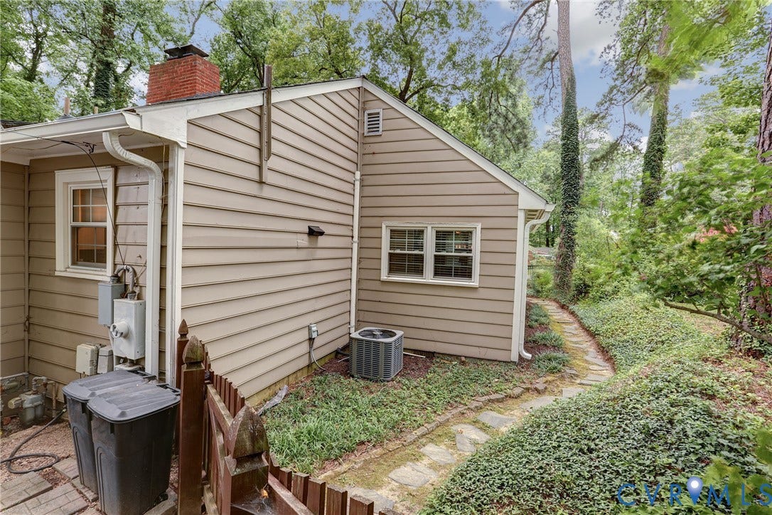 1401 Chowan Road, Henrico, VA 23229 Exterior siding with a red brick chimney, featuring a stone path, mature trees, and established ground cover