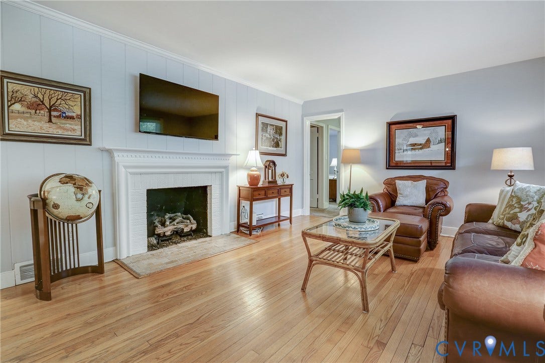 1401 Chowan Road, Henrico, VA 23229 Hardwood flooring throughout this room, featuring a white paneled accent wall and a fireplace with a detailed mantel