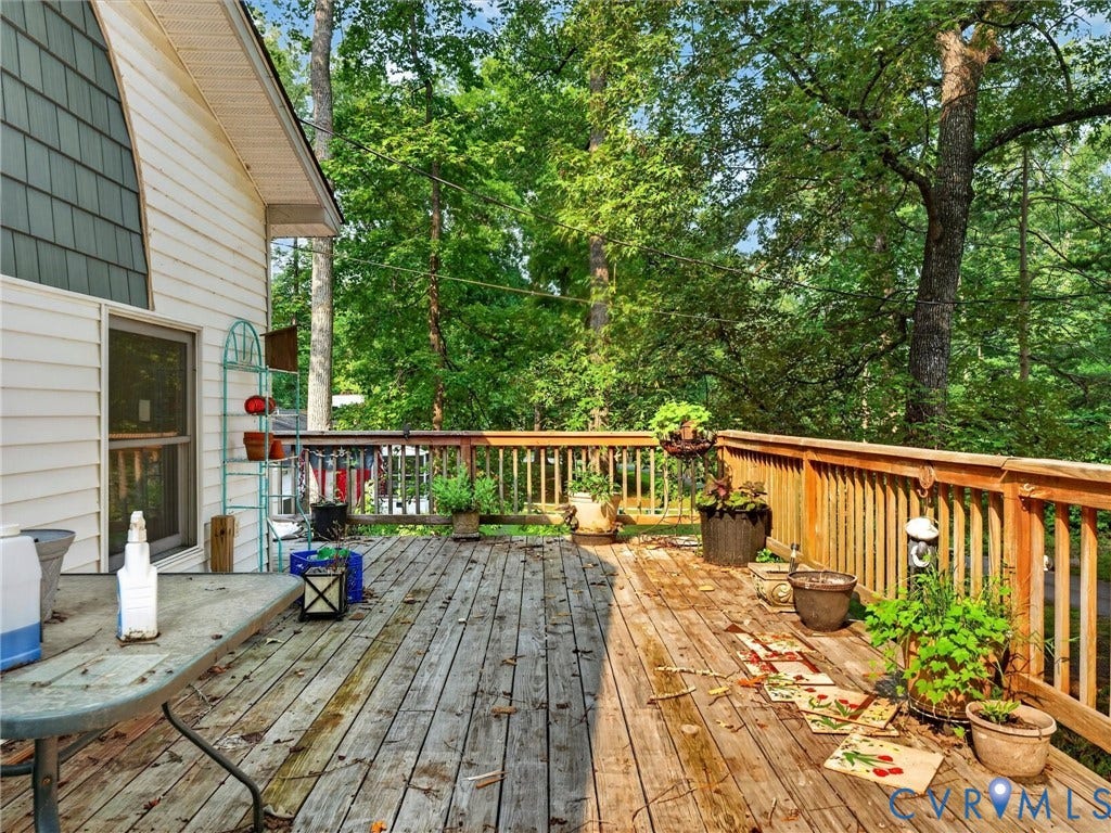 Expansive wood deck with natural wood railing, featuring a verdant tree-filled backdrop