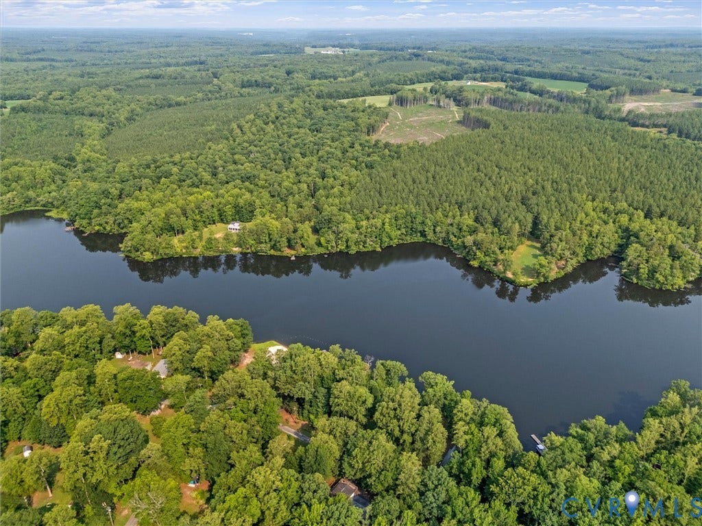 Expansive waterfront property featuring mature tree coverage, a private dock, and a serene lake