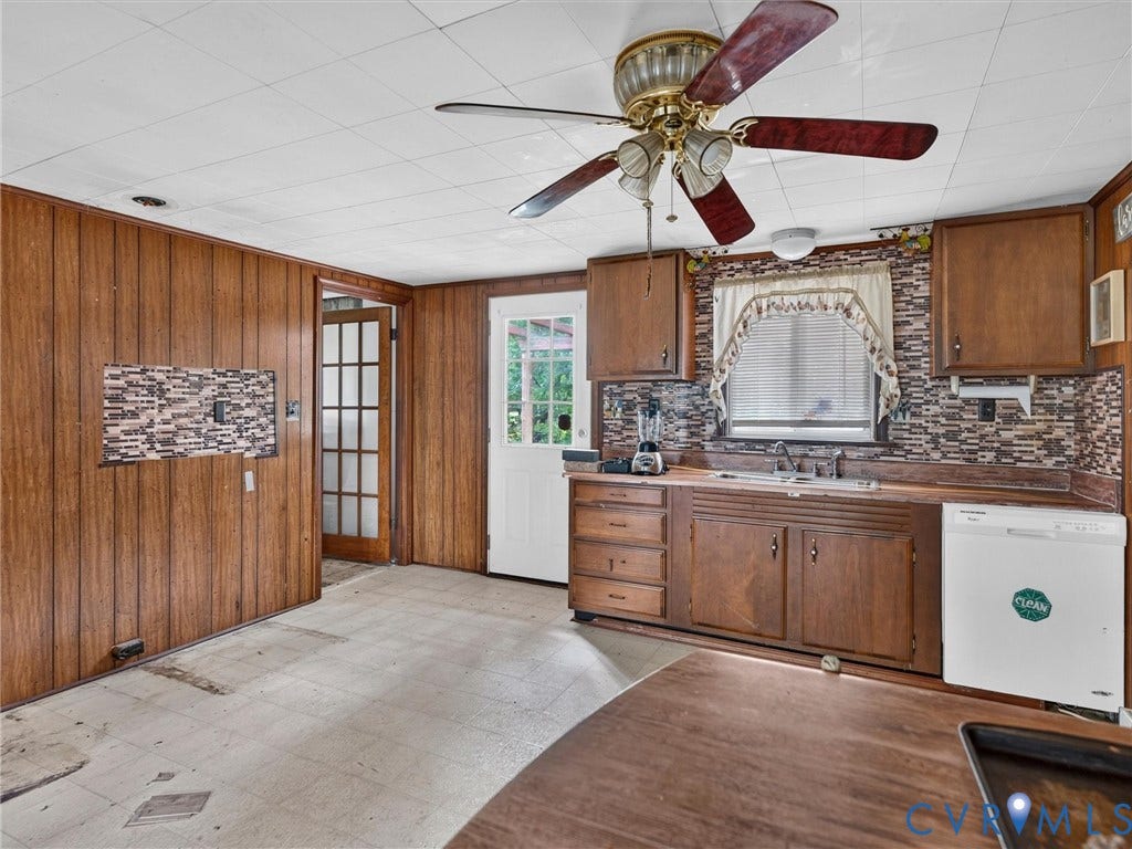 Kitchen featuring wood paneling, wood cabinetry, a mosaic tile backsplash, and an exterior door with glass panes