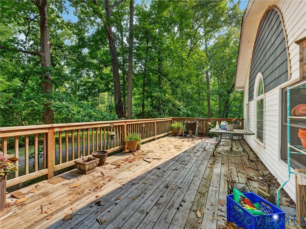 Spacious wood deck with natural wood railings, surrounded by mature trees