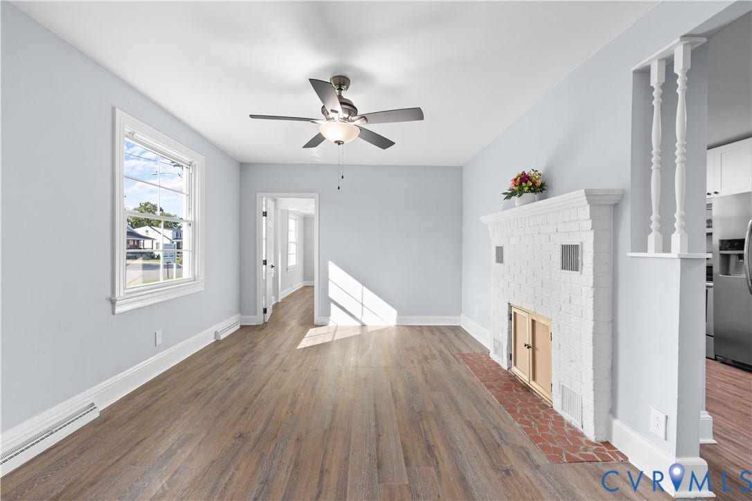 3516 Virginia Street, Woodlawn, Hopewell, VA 23860 Wood-finish flooring, white painted brick fireplace with hearth, ceiling fan with light fixture, white trim, and a window with natural light