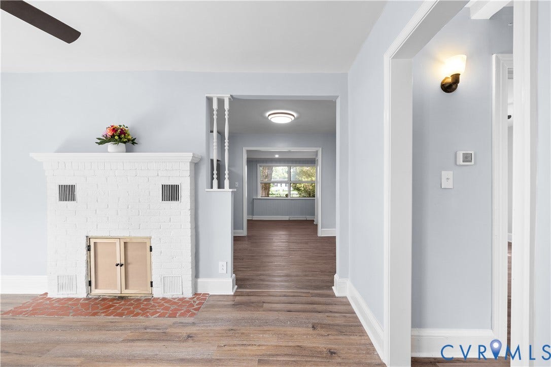 3516 Virginia Street, Woodlawn, Hopewell, VA 23860 Whitewashed brick fireplace with a brick hearth, wood-finish flooring, and a ceiling fan
