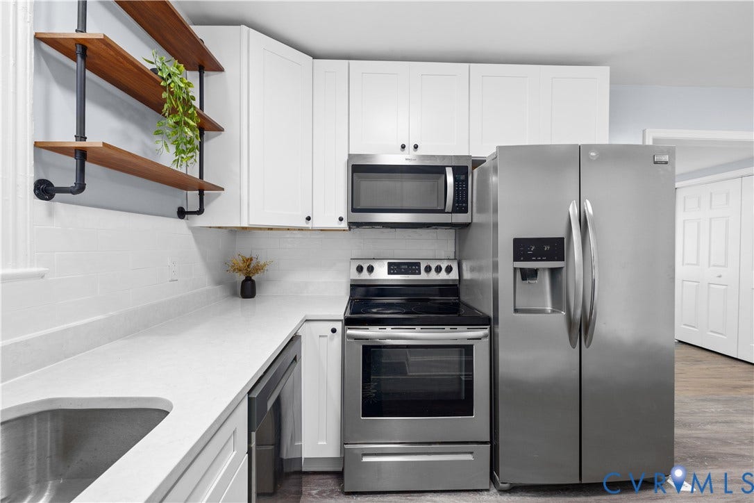 3516 Virginia Street, Woodlawn, Hopewell, VA 23860 White cabinetry, stainless steel appliances, open wood shelving, light-toned countertops, and a subway tile backsplash