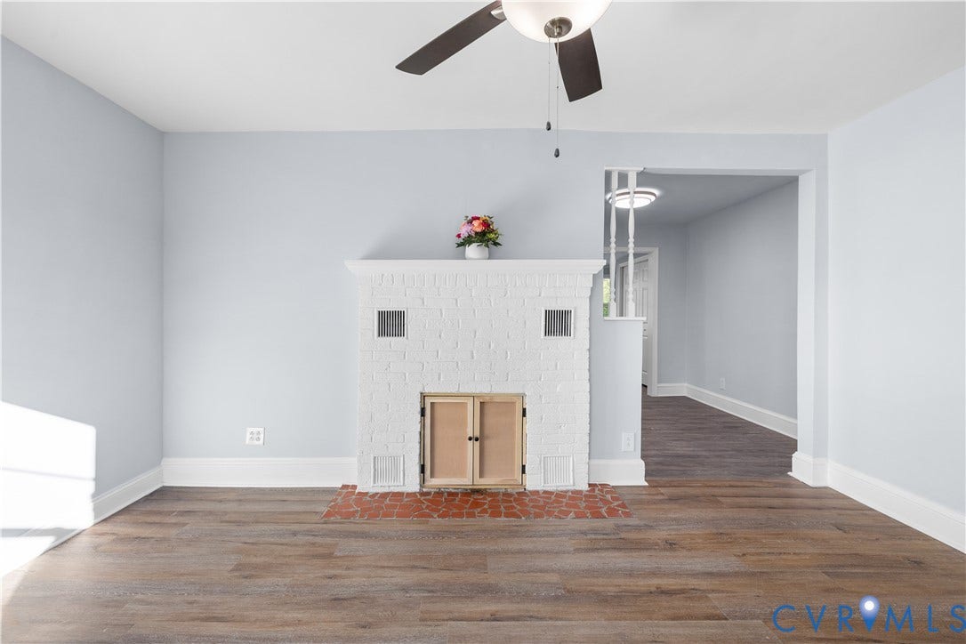 3516 Virginia Street, Woodlawn, Hopewell, VA 23860 Wood-finish flooring, white brick fireplace with terracotta hearth, ceiling fan, and painted light blue walls