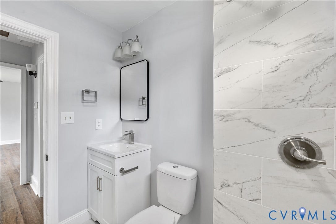 3516 Virginia Street, Woodlawn, Hopewell, VA 23860 White vanity with integrated sink, rectangular mirror, three-light vanity fixture, and tiled shower surround with brushed nickel fixtures