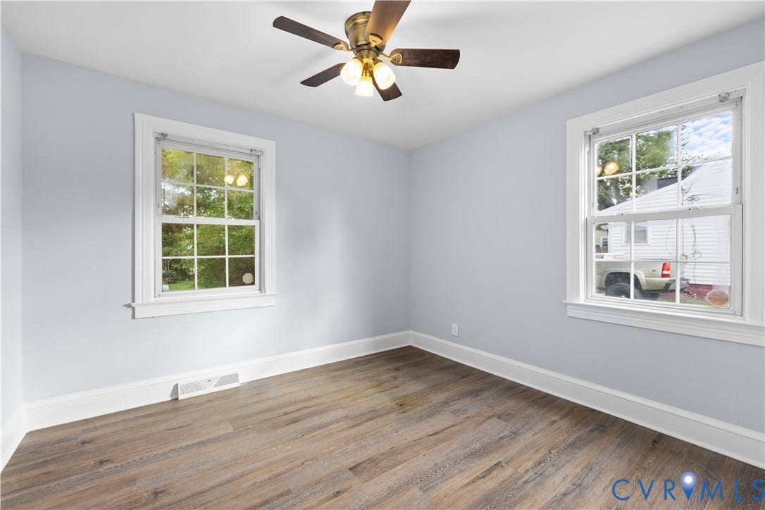 3516 Virginia Street, Woodlawn, Hopewell, VA 23860 Wood-finish flooring, light blue walls, two multi-pane windows with white trim, and a ceiling fan with integrated lighting