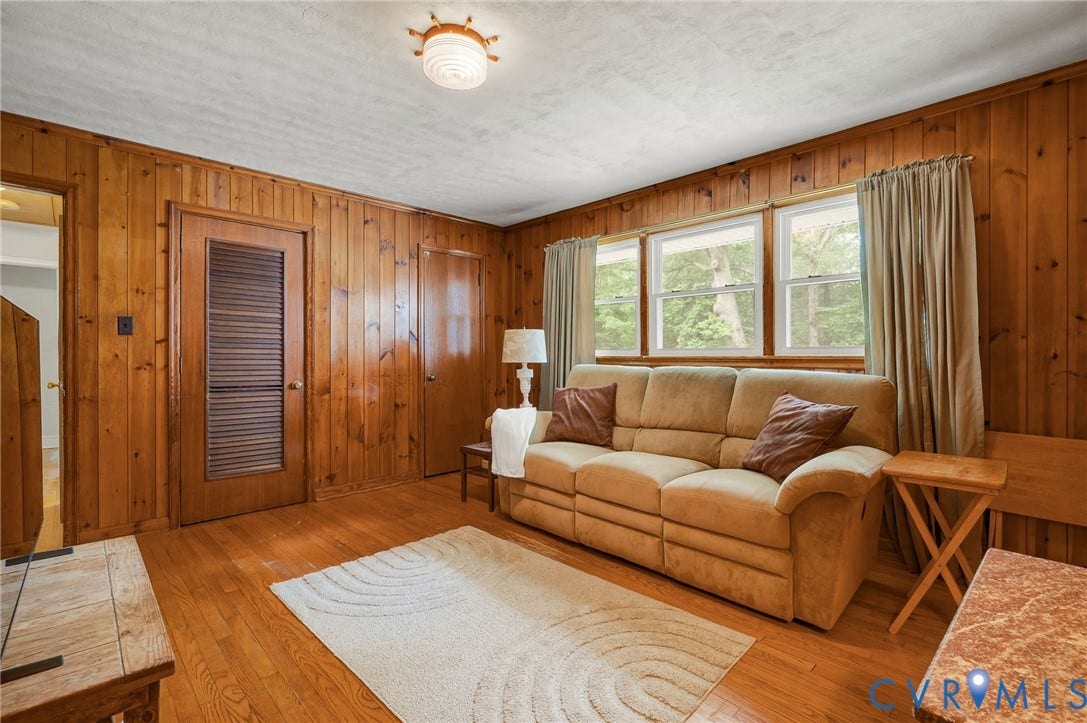 1910 Fon Du Lac Road, Henrico, VA 23229 Wood-paneled room featuring wood-finish flooring, three windows, a built-in louvered door, and a flush mount ceiling light fixture