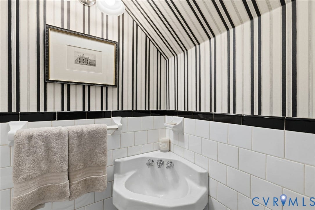 Corner pedestal sink with chrome fixtures and white subway tile wainscoting