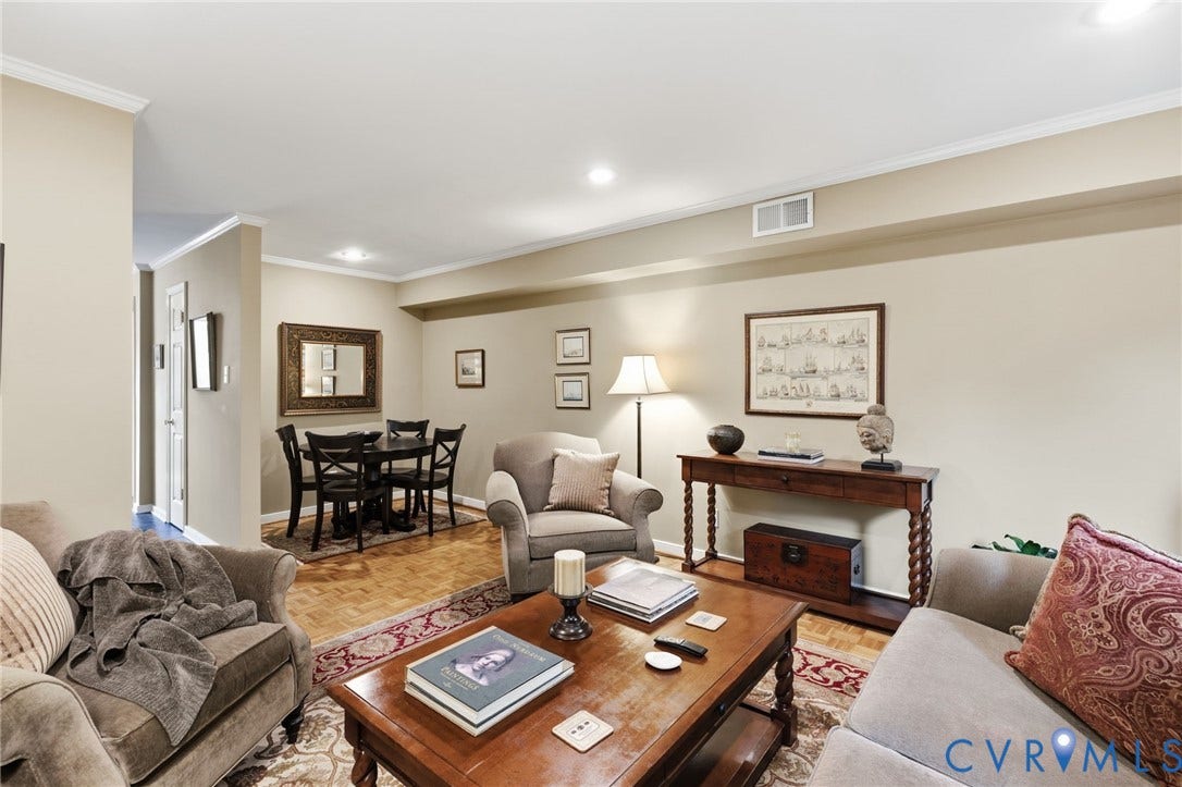 Open concept living and dining area featuring light-toned walls, recessed lighting, crown molding, wood-finish flooring, and a dining area with a dark wood table and chairs