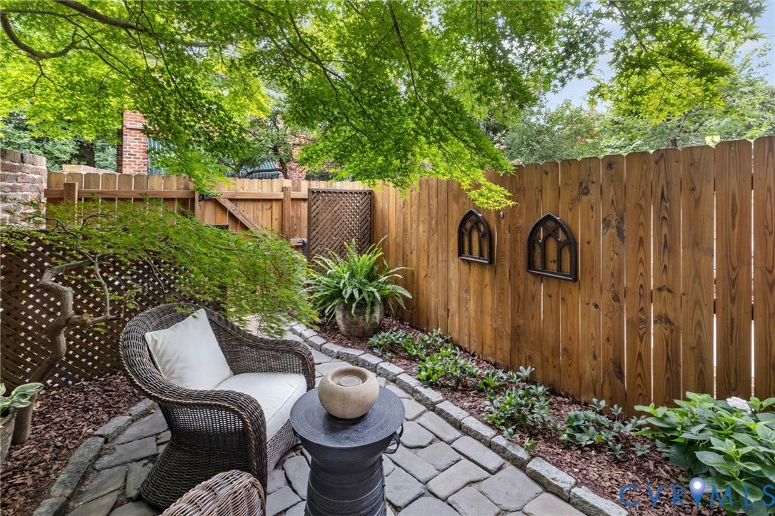 Private patio featuring natural stone pavers, wood fencing, mature trees, and established plantings