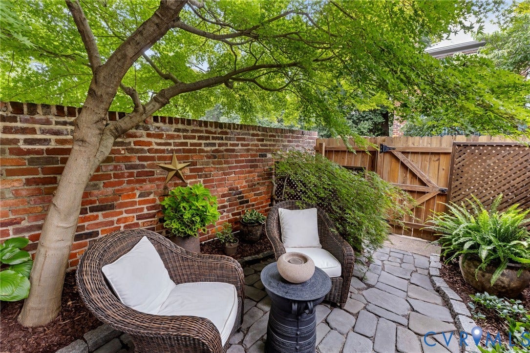 Private patio featuring a natural stone paver pathway, brick privacy wall, and mature tree