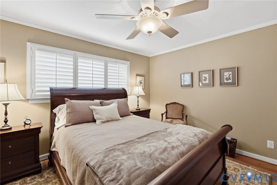 Room featuring hardwood flooring, crown molding, a ceiling fan with integrated lighting, and window shutters