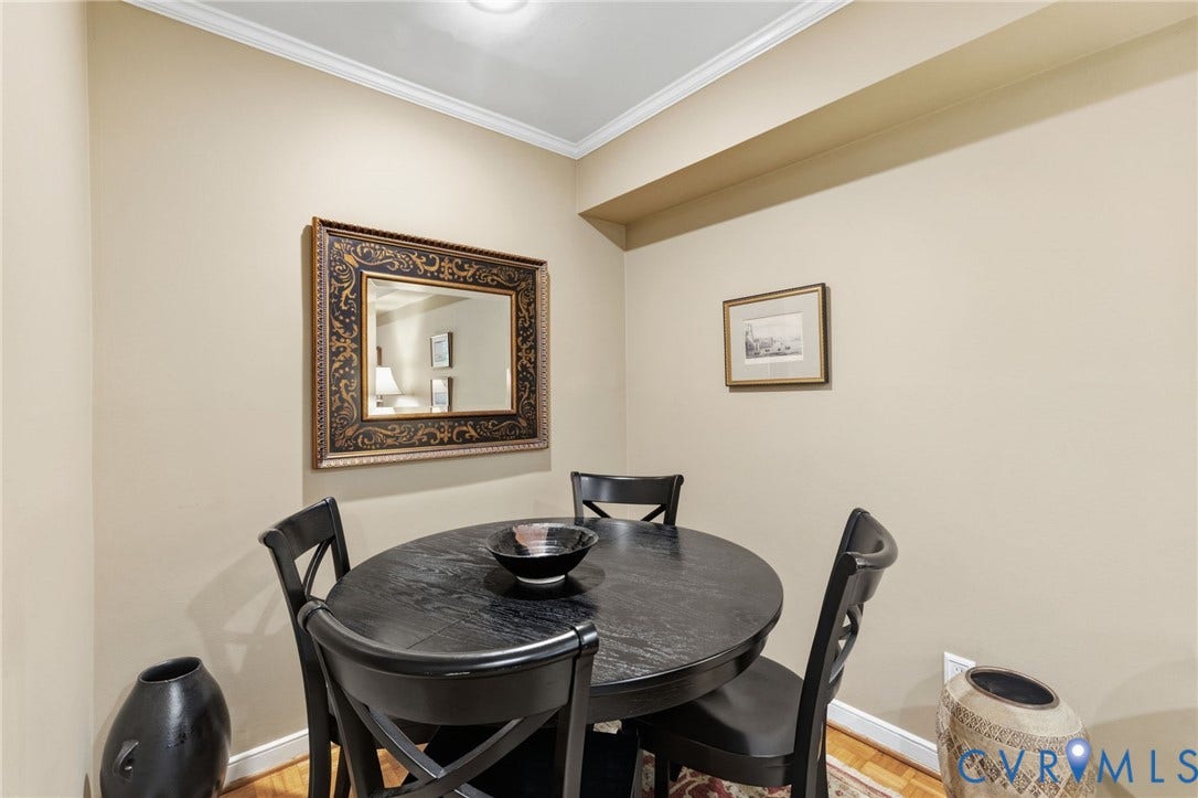 Recessed lighting illuminates a corner dining area with light-colored walls and white crown molding