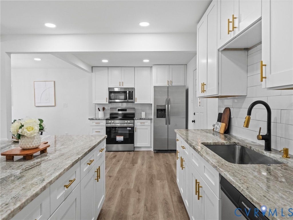 507 Grayson Avenue, Richmond, VA 23222 Modern kitchen featuring white cabinetry with gold-tone hardware, a center island, stainless steel appliances, and wood-finish flooring
