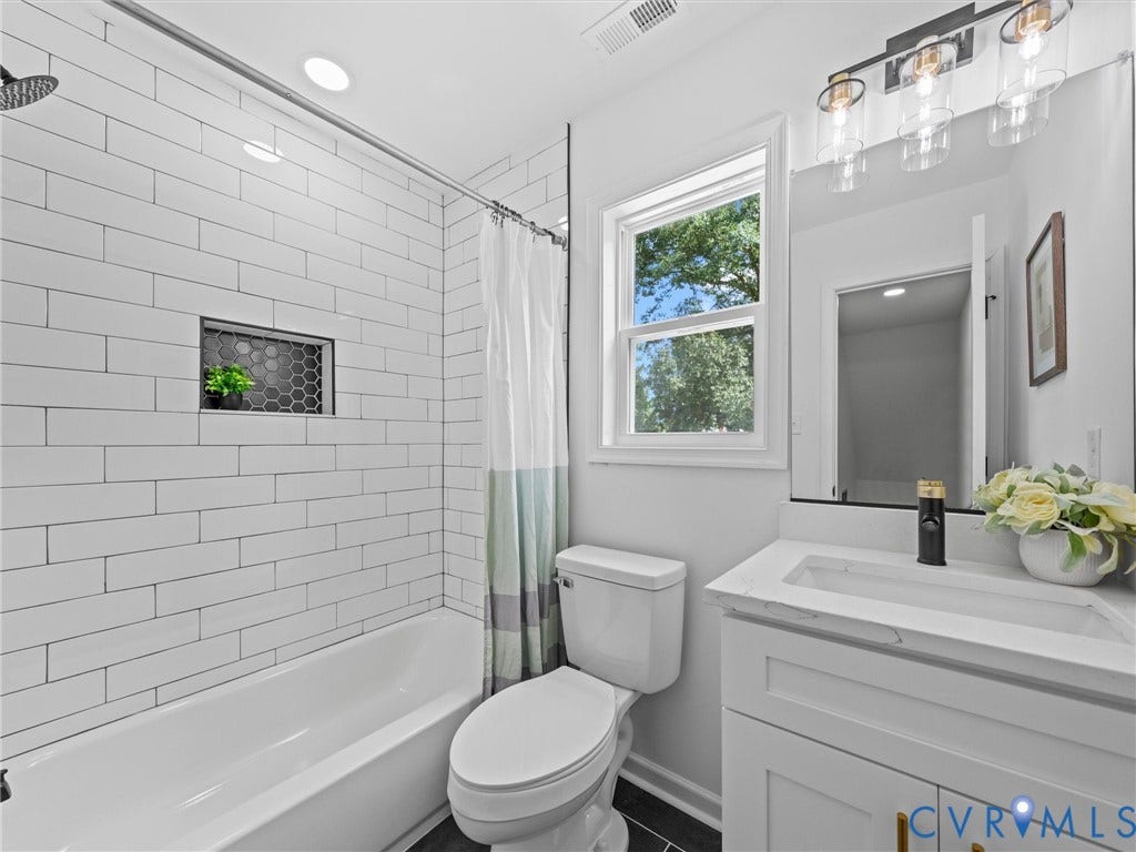 507 Grayson Avenue, Richmond, VA 23222 Bathroom featuring a white subway tile shower surround with an integrated honeycomb tile niche, a single vanity with a quartz countertop, and a window providing natural illumination