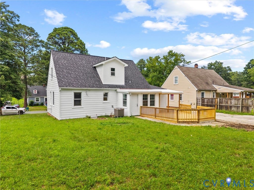 507 Grayson Avenue, Richmond, VA 23222 Rear exterior featuring white siding, a contrasting dark shingle roof, a generously sized wooden deck, a covered patio area, and a spacious grassy yard