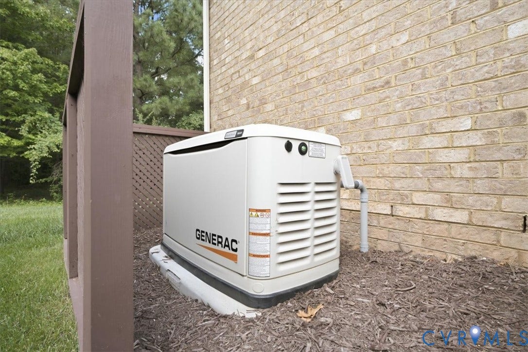 Generac standby generator installed 2025 on a concrete pad, complemented by a brick exterior and wood lattice screening, with mulched landscaping