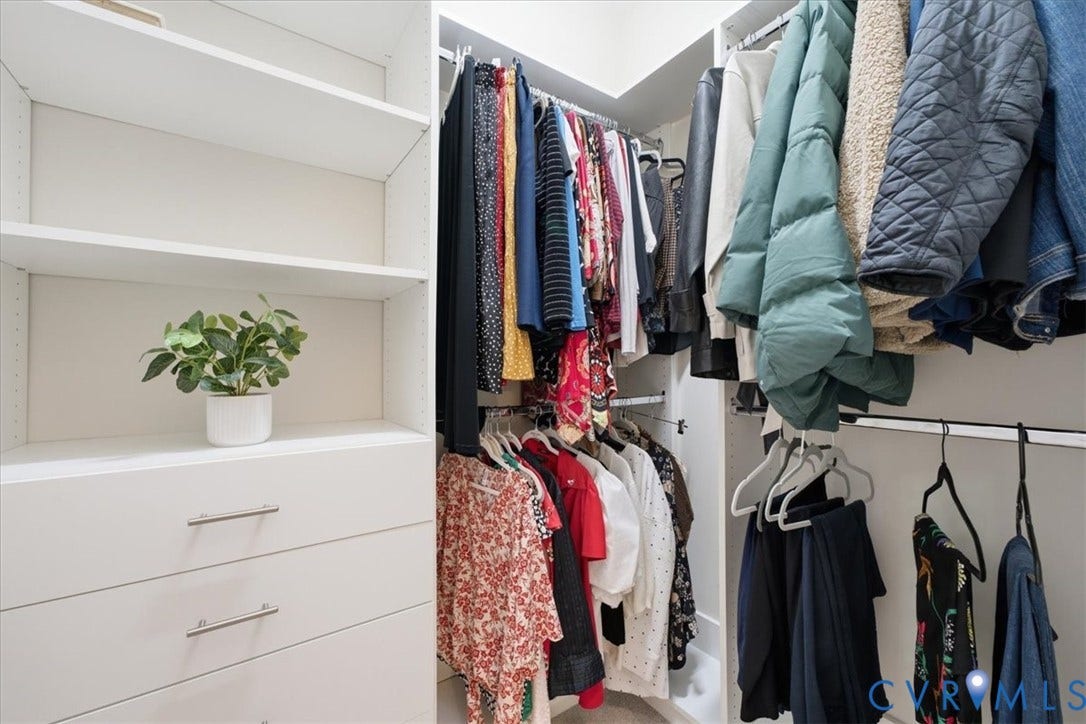 Custom closet system featuring white shelving, multiple hanging rods, and integrated drawers with brushed nickel pulls