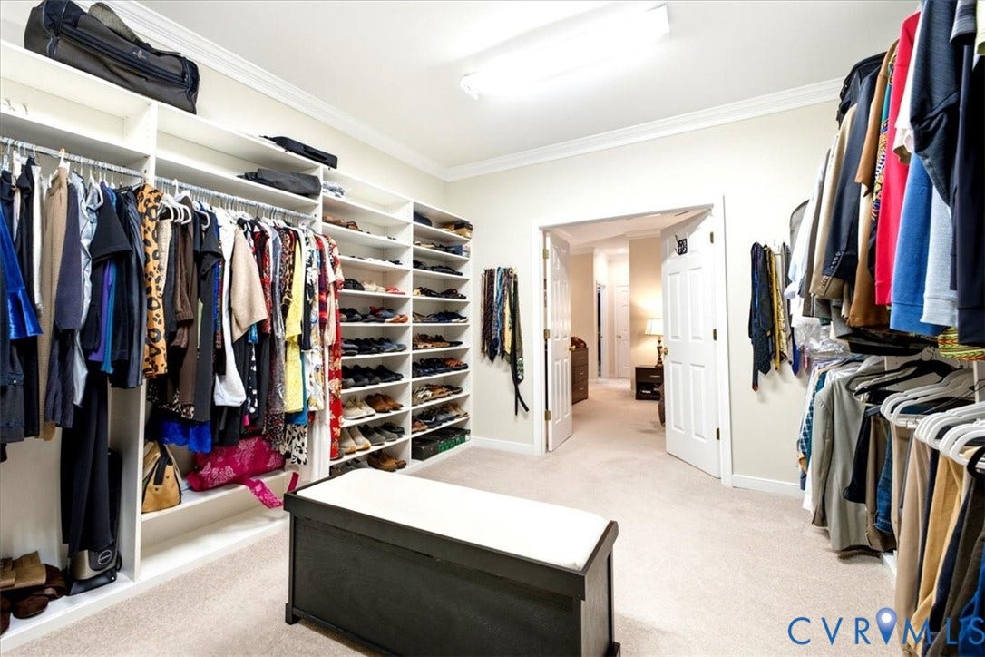 Spacious custom closet with extensive shelving, multiple hanging rods, and crown molding