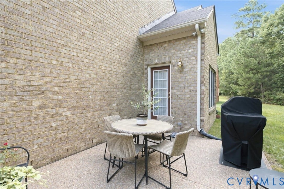 Exterior brick facade with a built-in outdoor light fixture, a glass-paneled door, and a concrete patio
