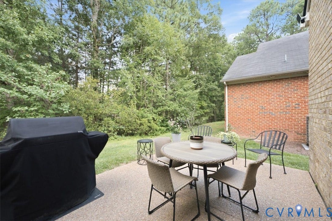 Expansive backyard patio featuring a textured concrete surface and mature perimeter trees