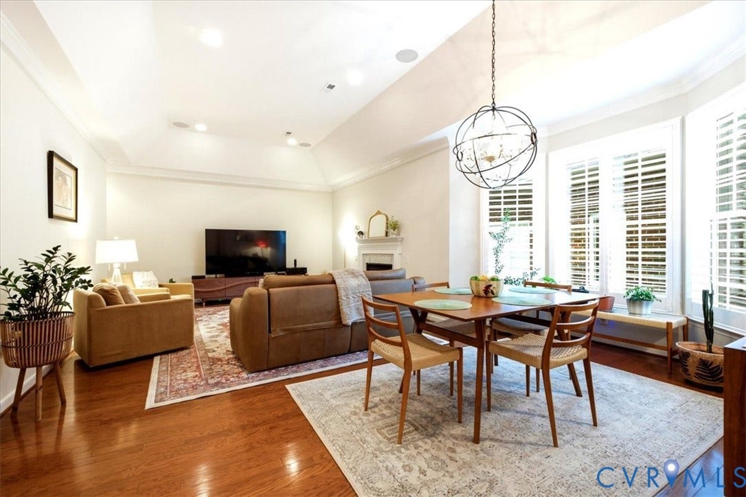 Hardwood flooring, tray ceiling, recessed lighting, bay windows with plantation shutters, and a spherical chandelier