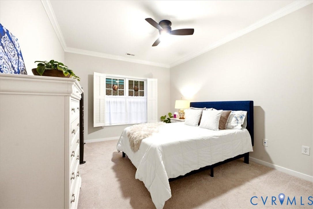Neutral wall color, crown molding, white window shutters, ceiling fan, and carpeted flooring