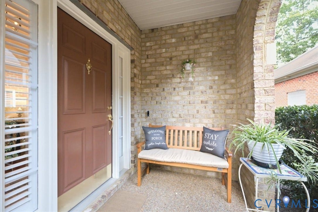 Brick facade with a covered entry, paneled front door, sidelight window, and decorative door knocker
