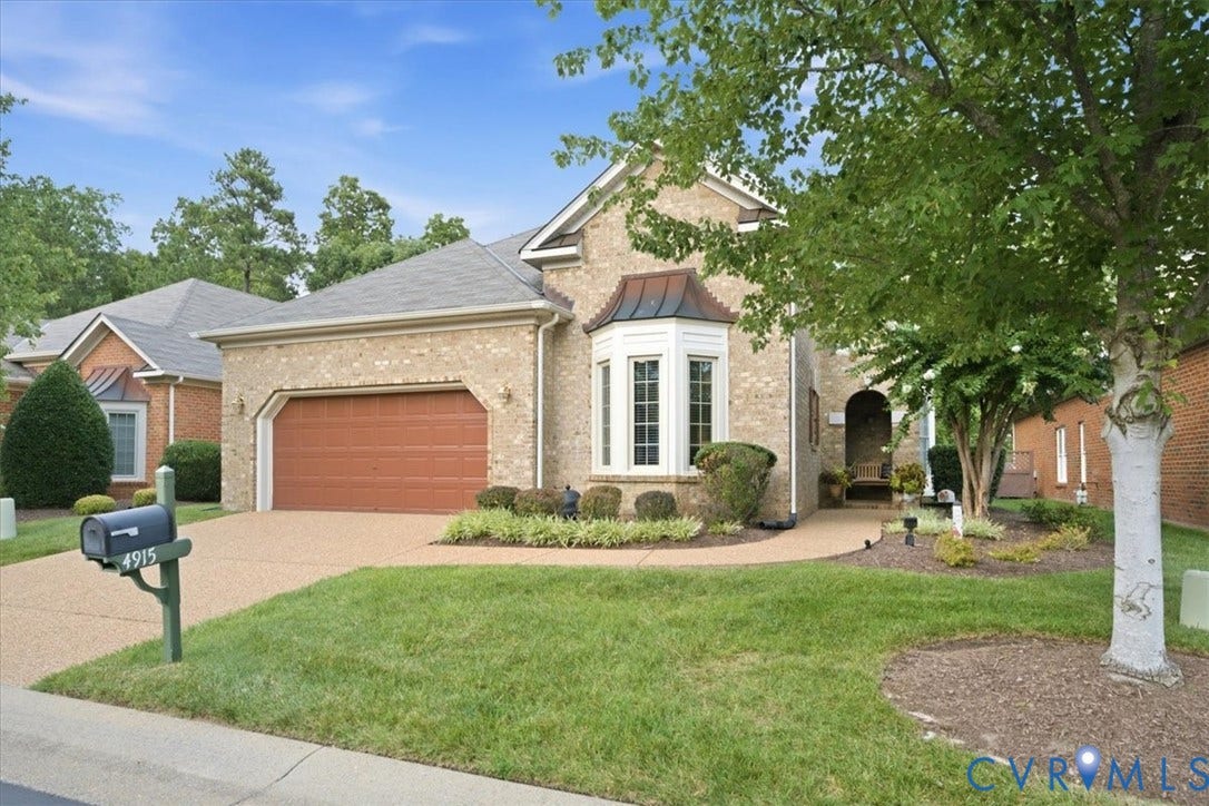 Brick exterior with a prominent bay window, attached garage, and a curved walkway leading to the entrance