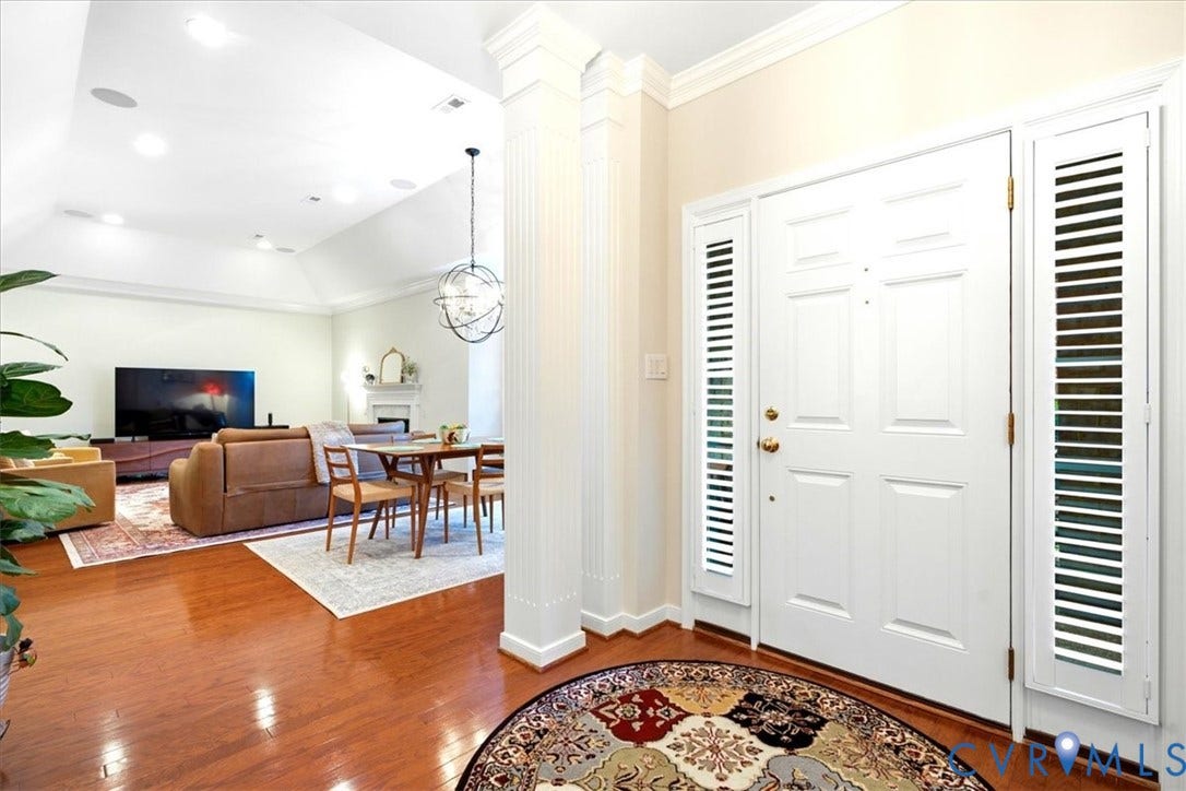 Hardwood flooring, recessed lighting, vaulted ceiling, decorative column, and a white paneled entry door with sidelights