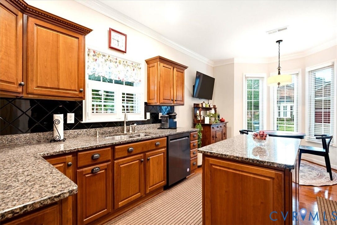 Full kitchen featuring wood cabinetry, speckled countertops, and a black diagonal tile backsplash