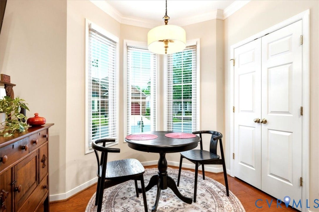 Bay window with white blinds, wood-finish flooring, white bi-fold doors, and a decorative ceiling light fixture